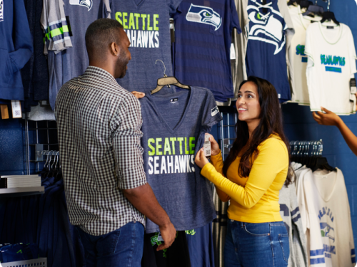A man and a woman selecting a blue Seattle Seahawks t-shirt in a store