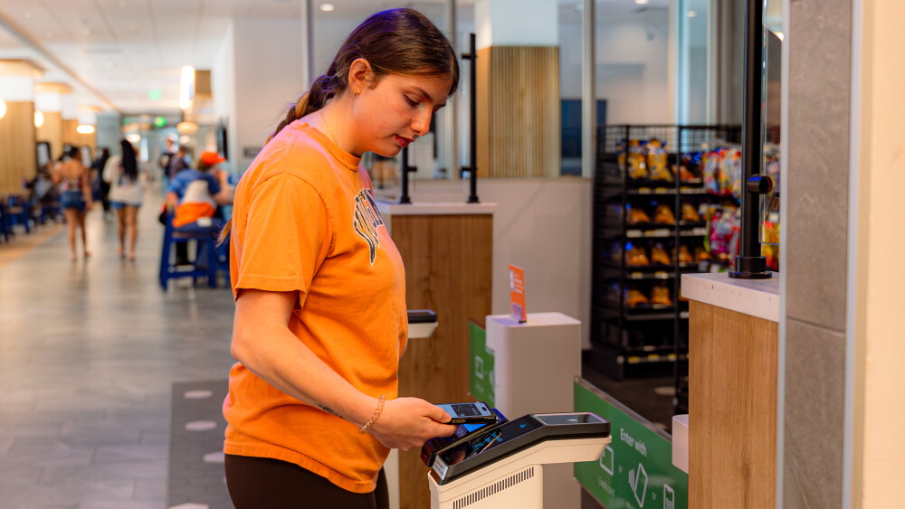 image of female student tapping to enter Just Walk Out technology-enabled store at the University of Virginia in Charlottesville, VA